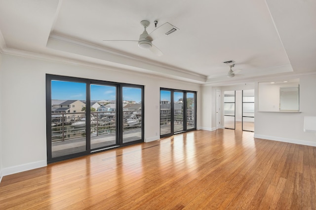 interior space with a raised ceiling, ornamental molding, ceiling fan, and light hardwood / wood-style flooring