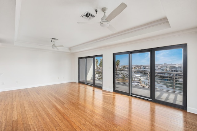 unfurnished room featuring ceiling fan, ornamental molding, a tray ceiling, and light wood-type flooring