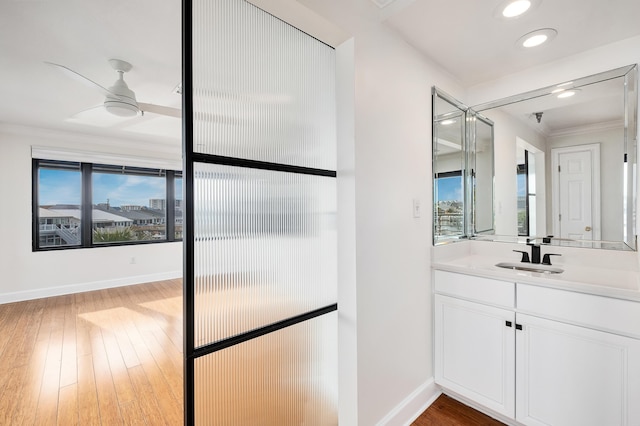 bathroom featuring vanity, hardwood / wood-style flooring, crown molding, and ceiling fan