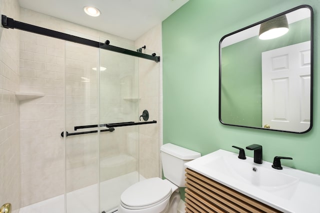 bathroom featuring toilet, vanity, and a shower with shower door