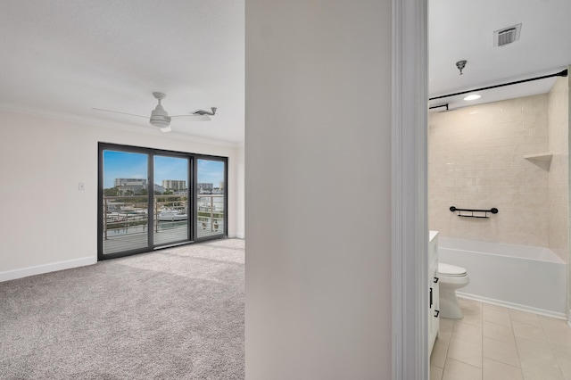 bathroom with crown molding, ceiling fan, toilet, and tiled shower / bath