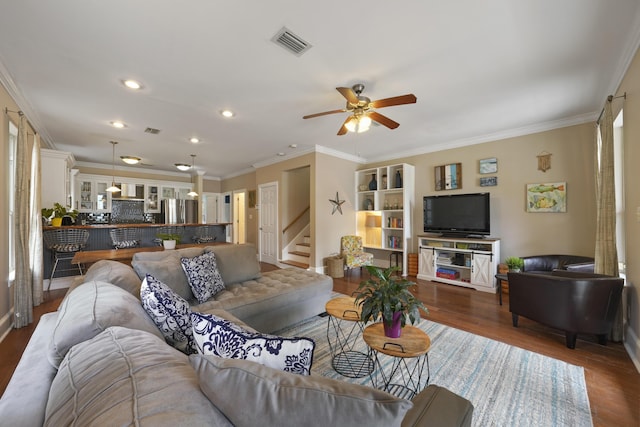 living room with dark wood-type flooring, ceiling fan, and ornamental molding