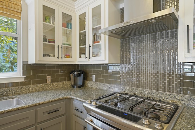 kitchen with decorative backsplash, plenty of natural light, stainless steel range with gas stovetop, and wall chimney exhaust hood