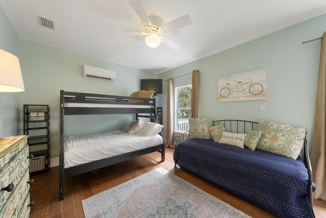 bedroom with dark wood-type flooring, a wall mounted AC, and ceiling fan