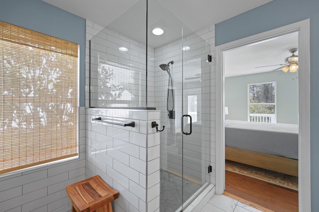 bathroom featuring tile walls, ceiling fan, and a shower with shower door