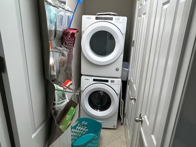 clothes washing area with stacked washer / drying machine and light tile patterned floors