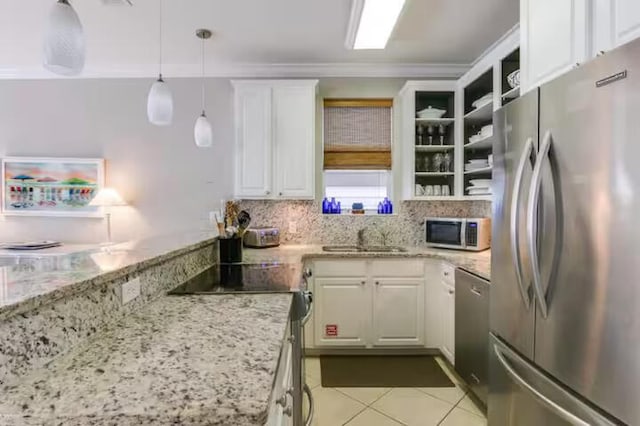 kitchen with decorative light fixtures, sink, white cabinets, light stone counters, and stainless steel appliances