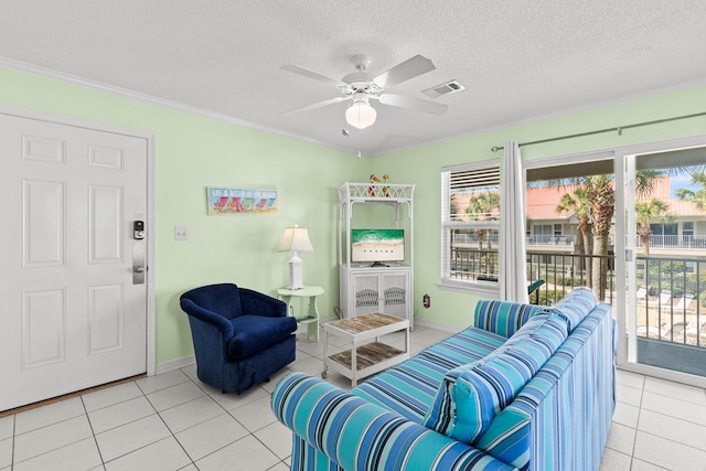 living room featuring light tile patterned flooring, crown molding, ceiling fan, and a textured ceiling