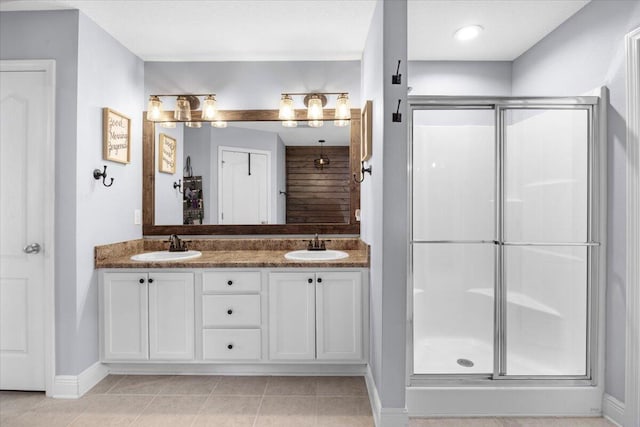 full bath featuring double vanity, a stall shower, a sink, and tile patterned floors