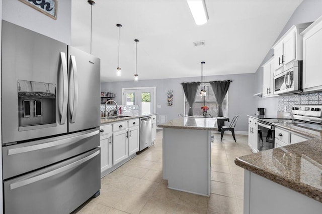 kitchen with a center island with sink, white cabinets, decorative light fixtures, stainless steel appliances, and a sink