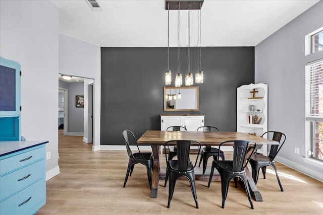 dining space featuring light wood-style floors, visible vents, and baseboards