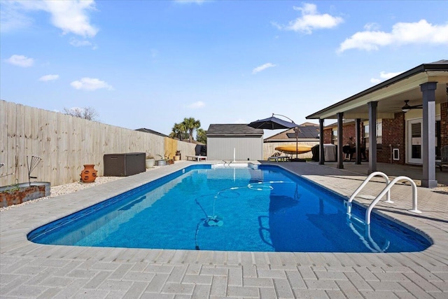 view of pool featuring a fenced in pool, a patio, a fenced backyard, ceiling fan, and an outbuilding