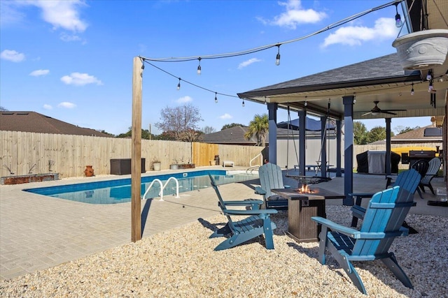 view of swimming pool with ceiling fan, an outdoor fire pit, a fenced backyard, a fenced in pool, and a patio area