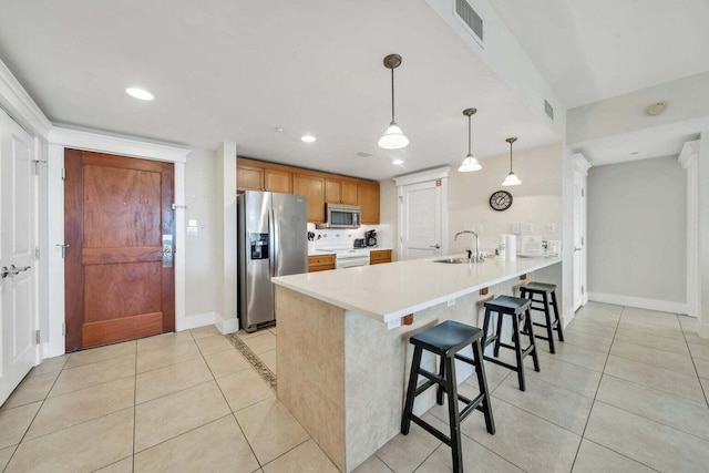 kitchen with appliances with stainless steel finishes, pendant lighting, sink, a kitchen breakfast bar, and kitchen peninsula