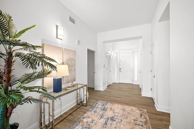 hallway with visible vents, baseboards, and wood finished floors