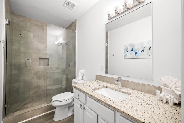 full bathroom with visible vents, toilet, wood finished floors, vanity, and a shower stall