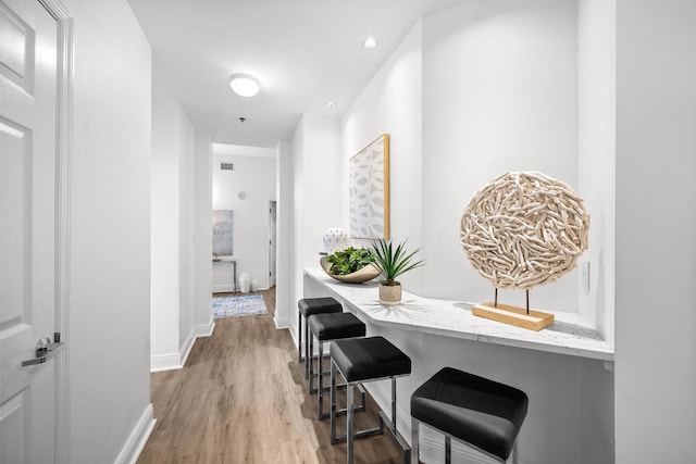 hall featuring recessed lighting, baseboards, and wood finished floors