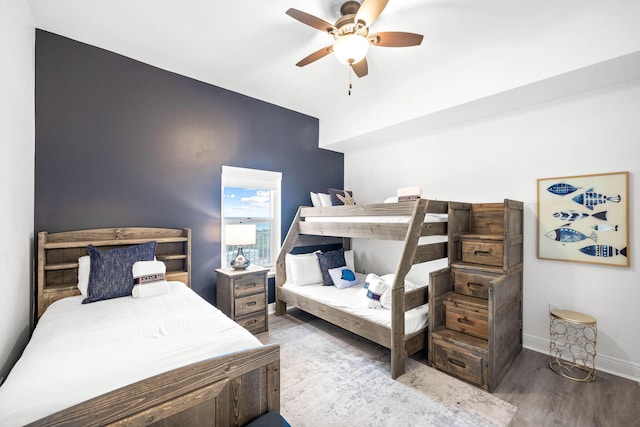 bedroom featuring a ceiling fan, baseboards, and wood finished floors