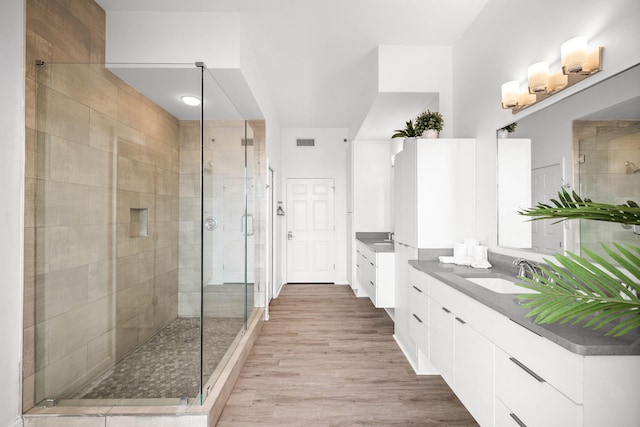 bathroom with a stall shower, visible vents, wood finished floors, and vanity