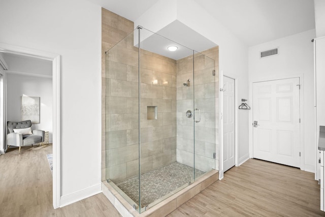 full bath with baseboards, a shower stall, visible vents, and wood finished floors