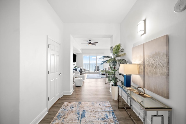 hall featuring dark wood-type flooring and baseboards