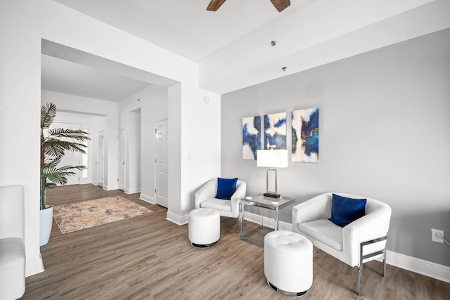 living area featuring ceiling fan, baseboards, and wood finished floors