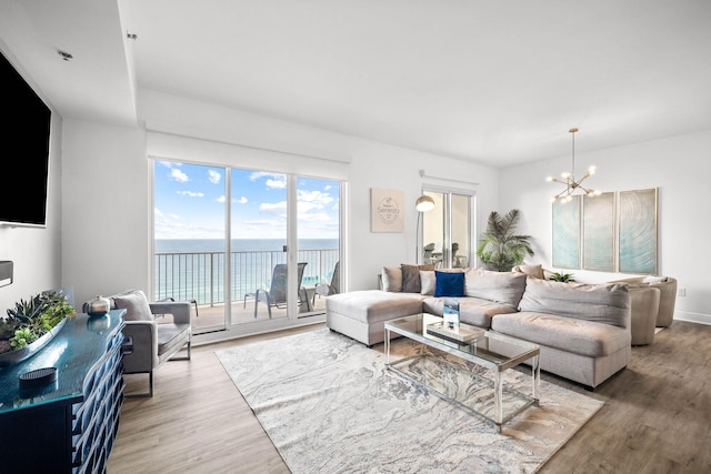 living room with a water view, baseboards, a chandelier, and wood finished floors