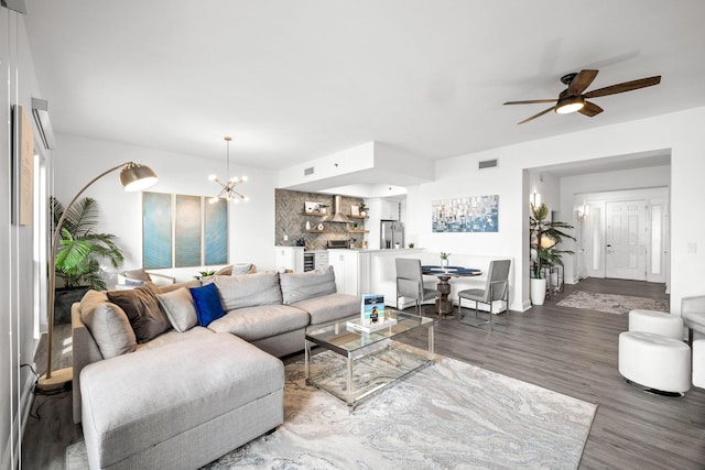 living room with ceiling fan with notable chandelier, wood finished floors, and visible vents