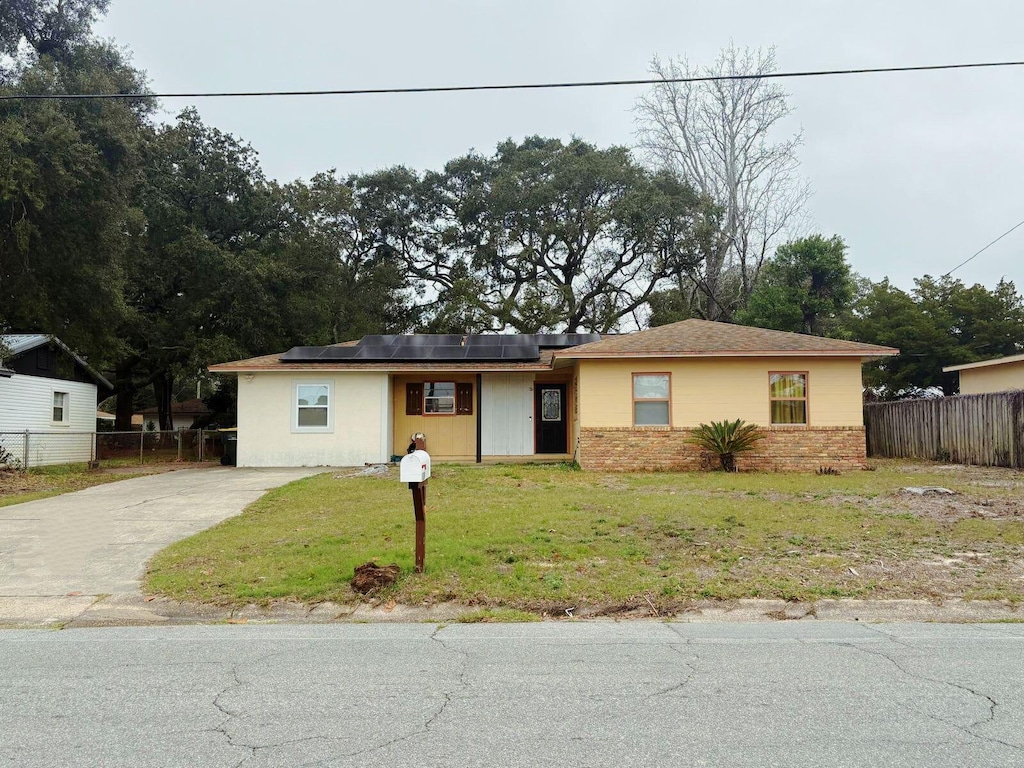 view of front of property featuring a front lawn and solar panels