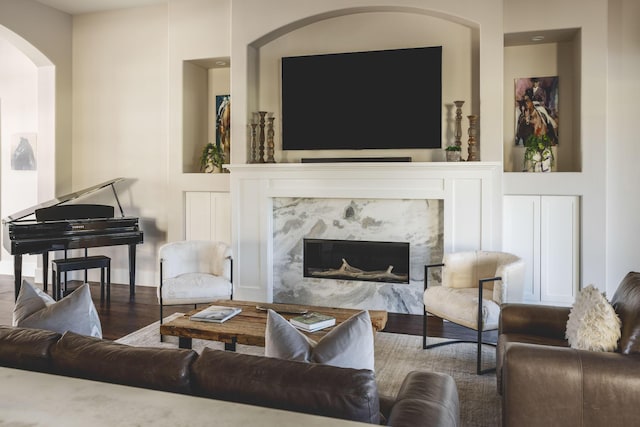 living room featuring a high end fireplace, arched walkways, and wood finished floors