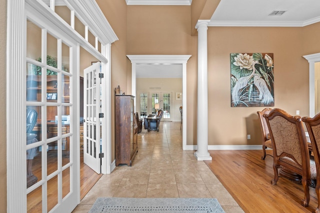 entryway featuring light hardwood / wood-style flooring, decorative columns, a high ceiling, ornamental molding, and french doors