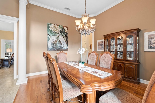 dining room featuring an inviting chandelier, crown molding, decorative columns, and light wood-type flooring