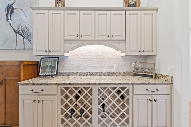 kitchen with white cabinetry, light stone countertops, and decorative backsplash