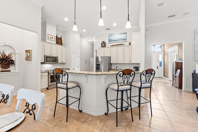 kitchen featuring light stone counters, appliances with stainless steel finishes, a breakfast bar, and light tile patterned floors