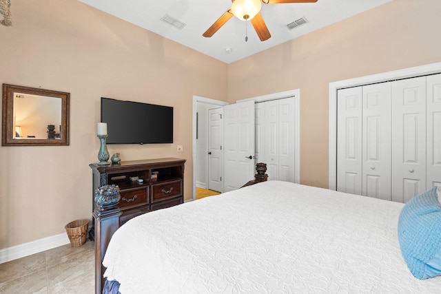 tiled bedroom with ceiling fan and two closets