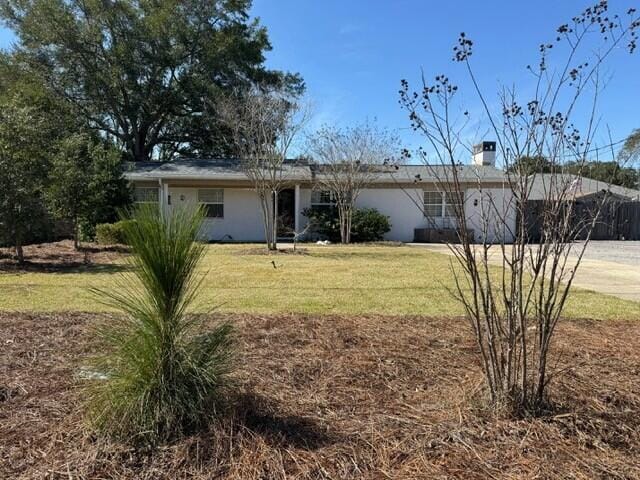 view of front of property with a front yard, a chimney, and stucco siding