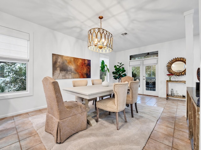 tiled dining area with a notable chandelier and french doors