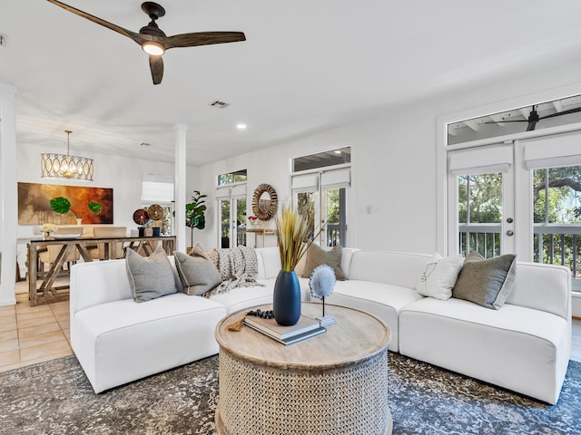 tiled living room featuring decorative columns and an inviting chandelier