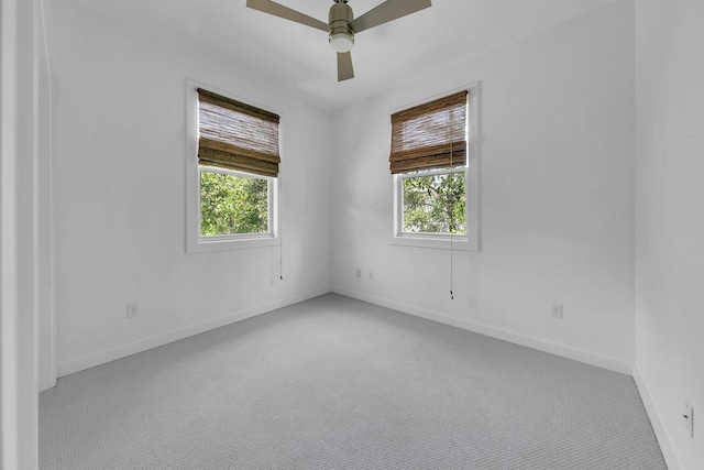 spare room with plenty of natural light, light colored carpet, and ceiling fan