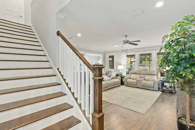 unfurnished living room with hardwood / wood-style flooring, ornamental molding, and ceiling fan