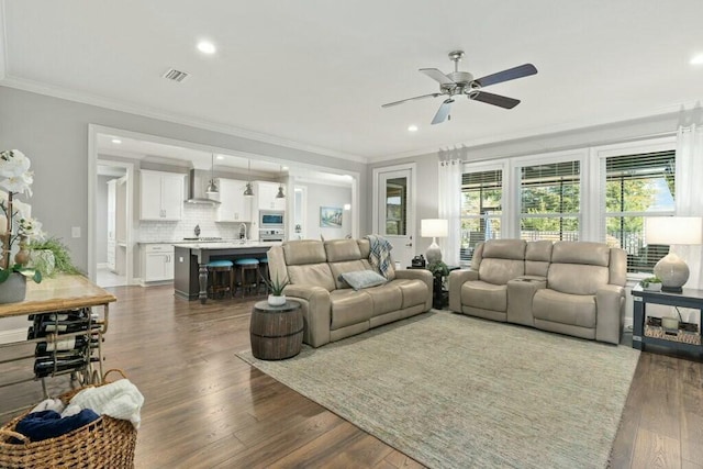 living room featuring dark hardwood / wood-style flooring, ornamental molding, and ceiling fan