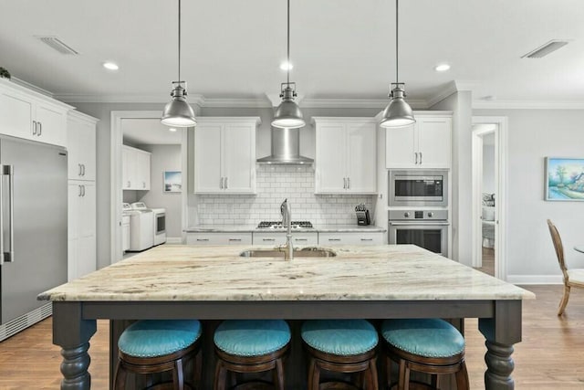 kitchen with pendant lighting, built in appliances, separate washer and dryer, and white cabinets