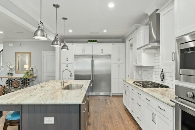 kitchen with stainless steel appliances, white cabinetry, a center island with sink, and decorative light fixtures