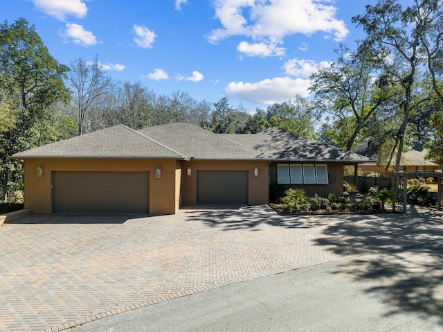 ranch-style home featuring a garage and decorative driveway