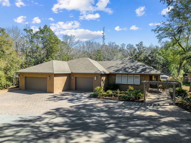 ranch-style house featuring a garage and decorative driveway