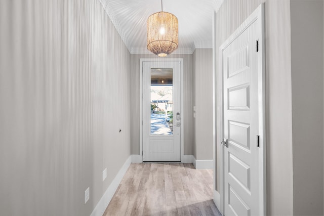 doorway to outside with crown molding, light wood-style flooring, and baseboards