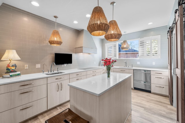 kitchen featuring light countertops, a barn door, a kitchen island, a sink, and premium range hood