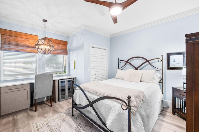 bedroom with light wood finished floors, beverage cooler, ornamental molding, a closet, and ceiling fan with notable chandelier