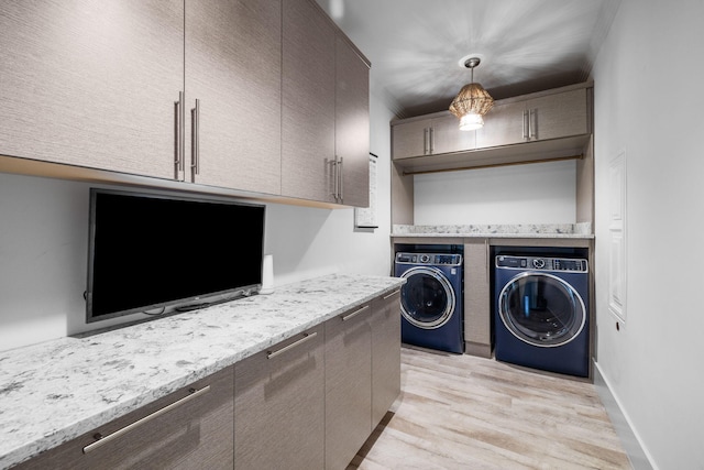 washroom with light wood-style flooring, cabinet space, washer and clothes dryer, and baseboards