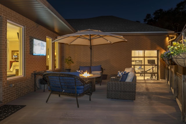 patio at night with an outdoor living space with a fire pit